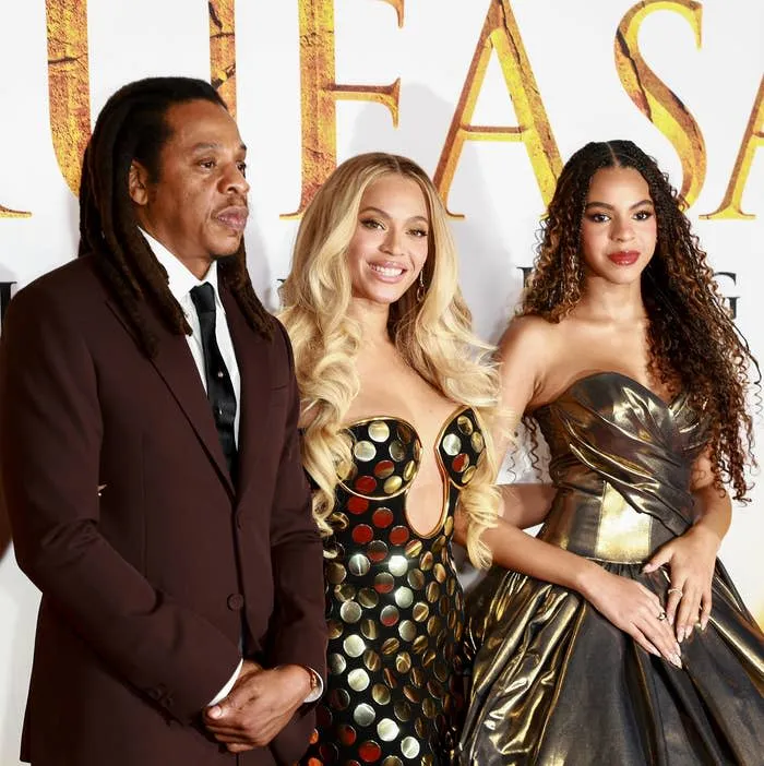 Jay-Z, Beyoncé, and Blue Ivy pose on a red carpet in elegant attire