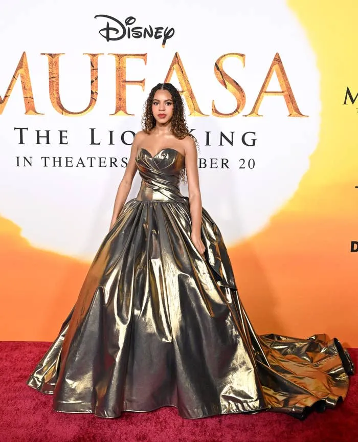 Blue Ivy Carter in a glamorous long, strapless, metallic gown posing on a red carpet